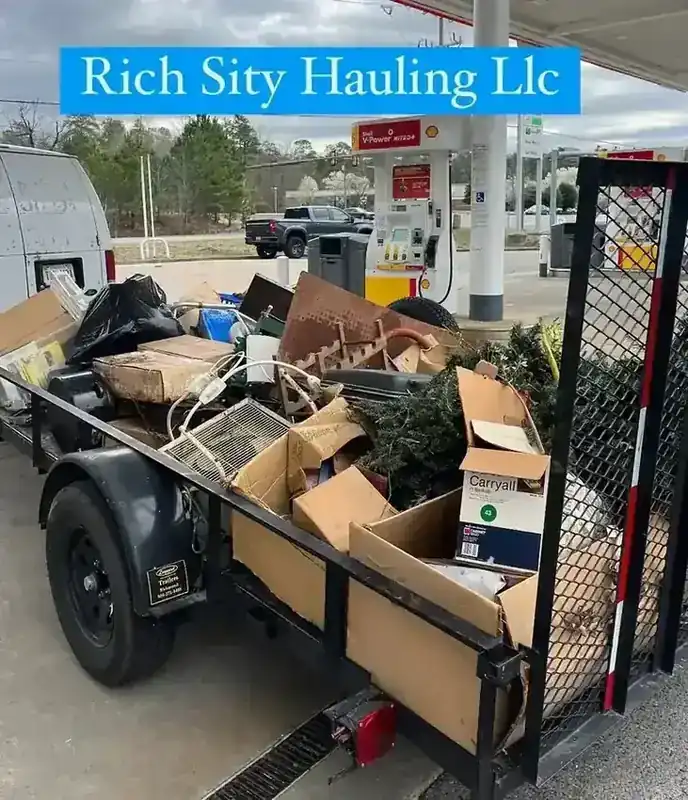 A fully loaded Rich Sity Hauling trailer parked at a Shell gas station between jobs