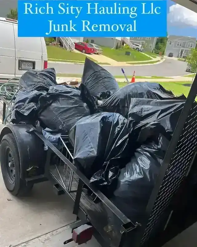 A Rich Sity Hauling trailer loaded with bagged household junk on a Richmond driveway