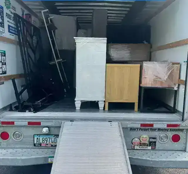 A loaded U-Haul box truck interior with the ramp down, ready for a Rich Sity Hauling move