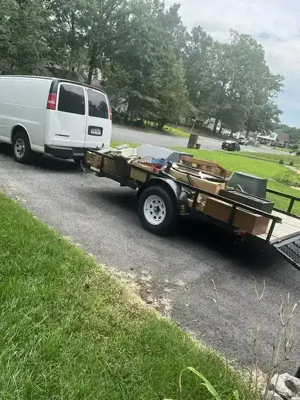 The Rich Sity Hauling van and loaded trailer parked in a suburban Richmond driveway