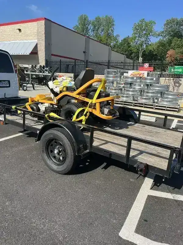 A Cub Cadet riding mower strapped to the Rich Sity Hauling trailer on a Tractor Supply forecourt