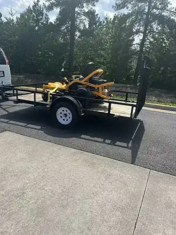 A Cub Cadet riding mower strapped to the Rich Sity Hauling trailer at a Tractor Supply store