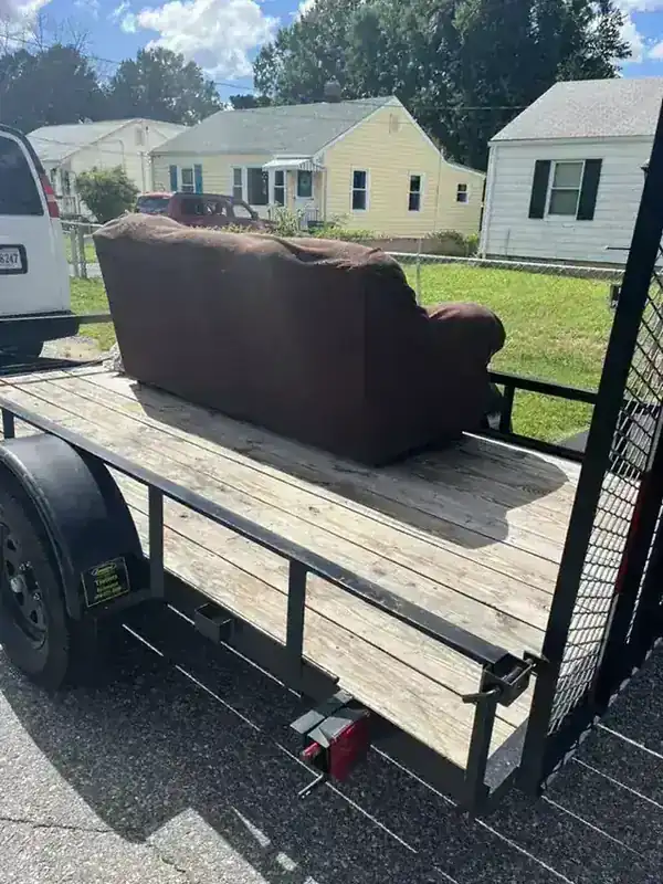 A brown couch strapped to the Rich Sity Hauling trailer on a Richmond bungalow street