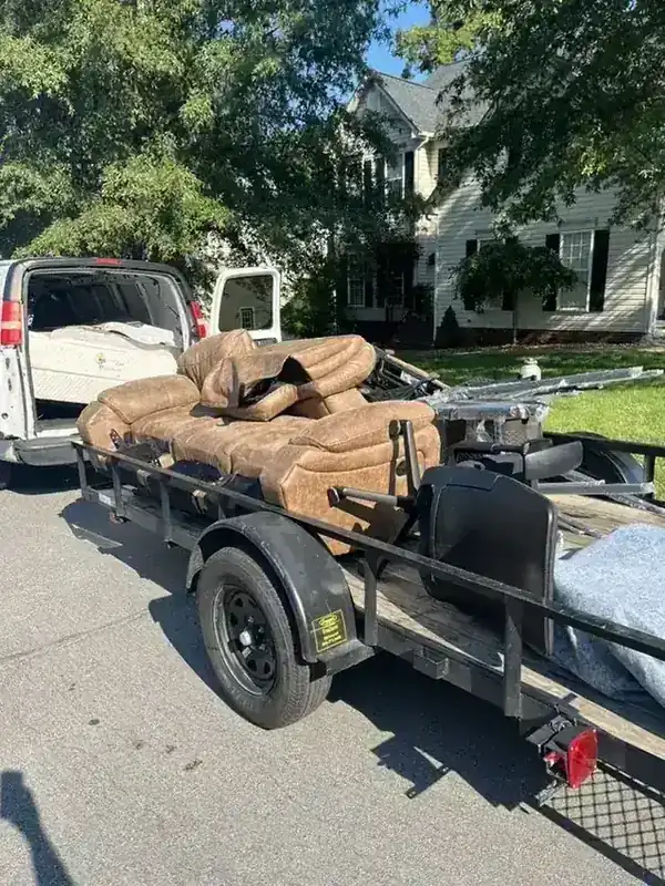 A leather sectional and mattress loaded on the Rich Sity Hauling trailer outside a Richmond home