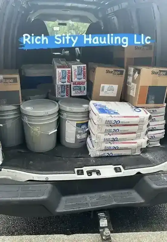 A Rich Sity Hauling van loaded with buckets, tape, and joint compound for a material transport run