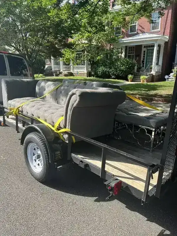 A grey tufted sofa strapped to the Rich Sity Hauling trailer outside Fan District rowhouses in Richmond